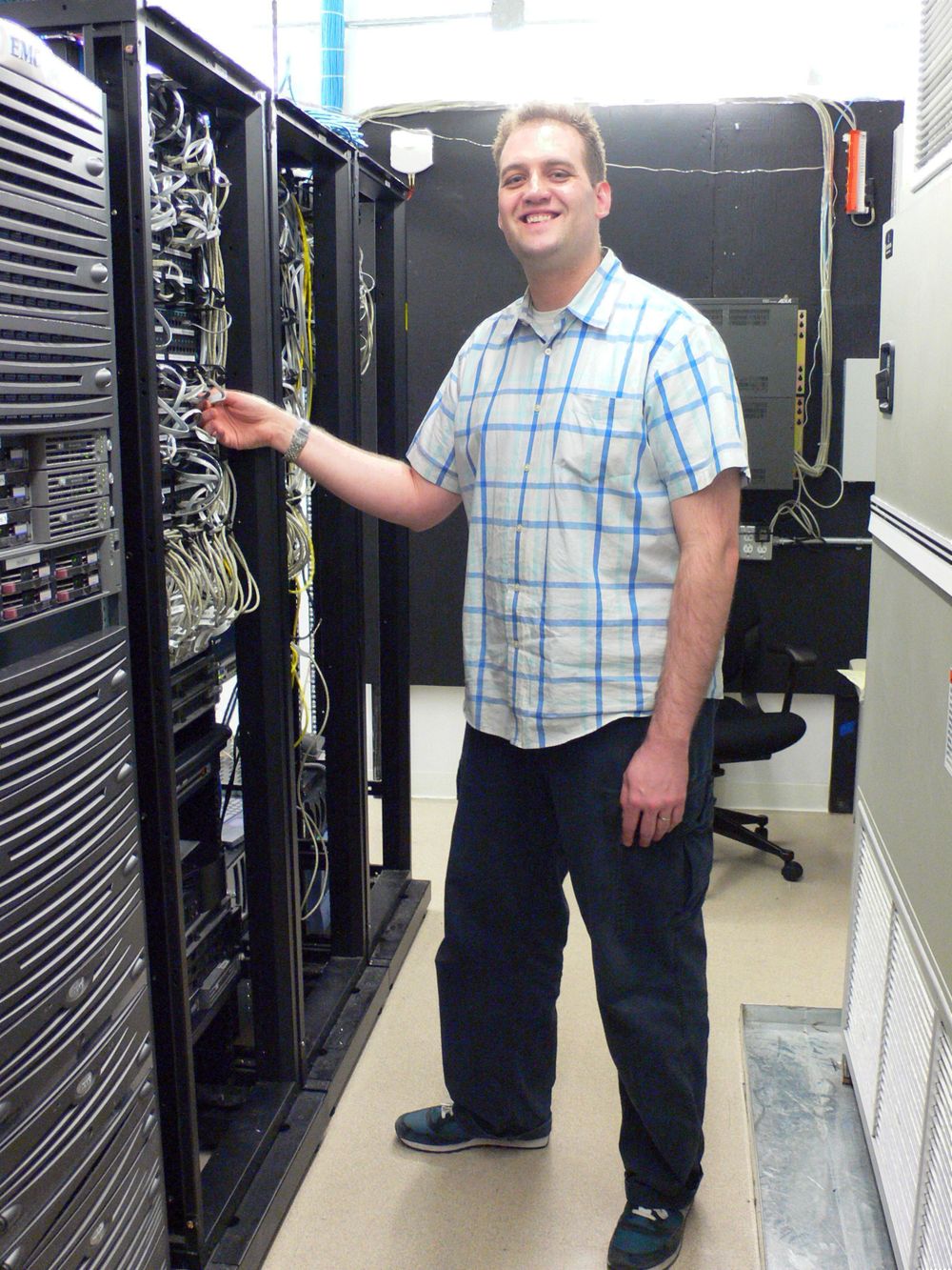System administrator working at a server console with cabling visible in the rack.